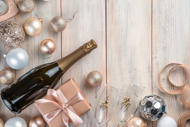 Kerstachtergrond met champagne, geschenkdoos en kerstboomspeelgoed op beige achtergrond. Bovenaanzicht, kopieer ruimte.