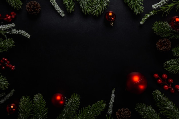 Kerstachtergrond met dennentakken, cadeau of cadeau en rode bal op donkere en zwarte achtergrond. Bovenaanzicht met kopieerruimte