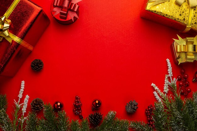 Kerstachtergrond met dennentakken, cadeau of cadeau en rode bal op rode bannerachtergrond. Bovenaanzicht met kopieerruimte