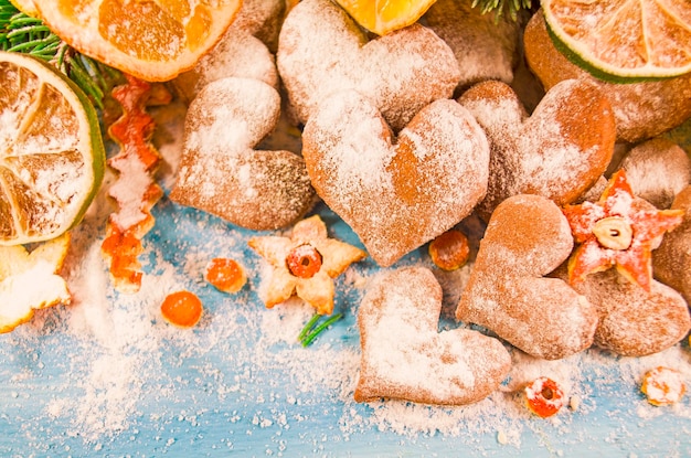 Kerstachtergrond met dennentakkenkoekjes bestrooid met poedersuiker op een houten bord