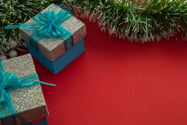 Kerstachtergrond met geschenkdozen met blauwe strik groene takken en rode achtergrond
