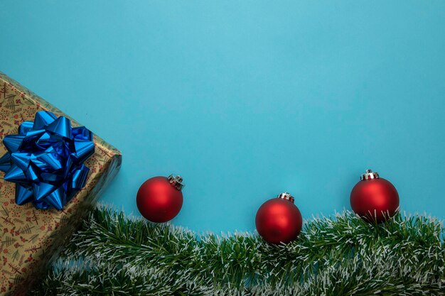 Kerstachtergrond met gouden geschenken, groene slinger en rode bollen, ruimte voor blauwe tekst