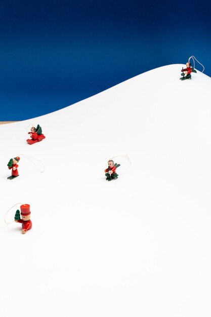 Kerstachtergrond met kleine boomversieringsfiguren die sneeuwen in een berg van wit papier