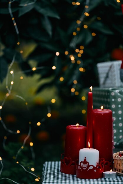 Kerstachtergrond met knusse kaarsen, sinaasappels en wazige kerstverlichting