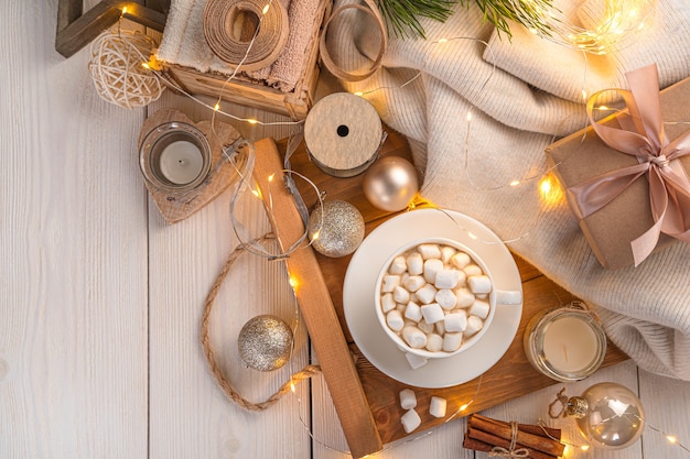 Kerstachtergrond met marshmallow-koffie en kerstversiering in het licht van een brandende slinger. bovenaanzicht, kopieer ruimte.