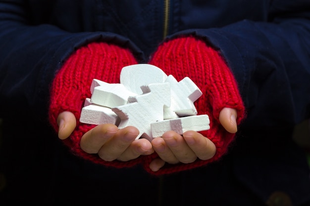 Kerstachtergrond - vrouwelijke handen in rode handschoenen houden nieuwjaarsspeelgoed vast