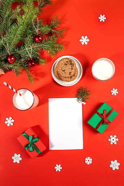 Kerstarrangement van melkglazen koekjes wit vel geschenkdozen dennentakken op rood