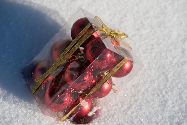 Kerstbal in doos op verse sneeuw op mooie zonnige winterdag met lange schaduw