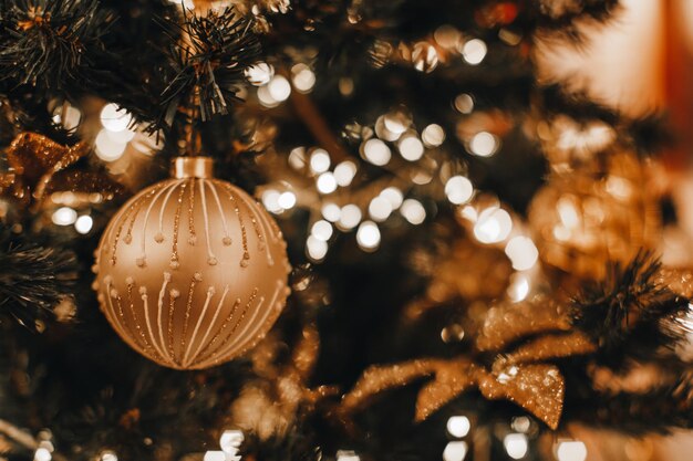 Kerstbal met gouden glitterdecor hangend aan de feestelijke kerstboomtakken Winter