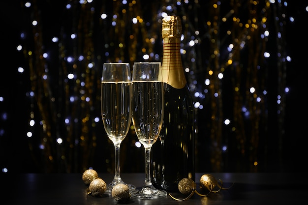 Kerstballen, champagneglazen en fles op onscherpe ruimte, kopie ruimte