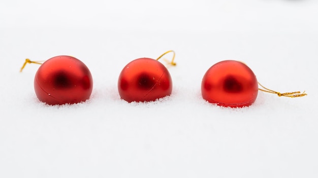 Kerstballen in de sneeuw drie rode kerstballen