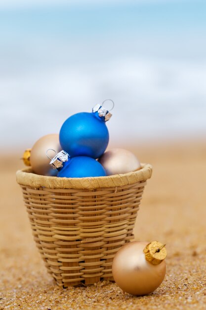 Kerstballen in een mand aan de zandige kust van de oceaan