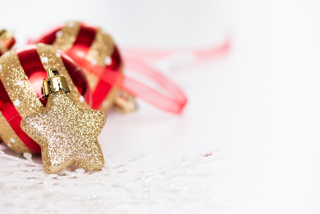 Kerstballen met gouden ster, dennenappels en sneeuwvlok op abstracte achtergrond.