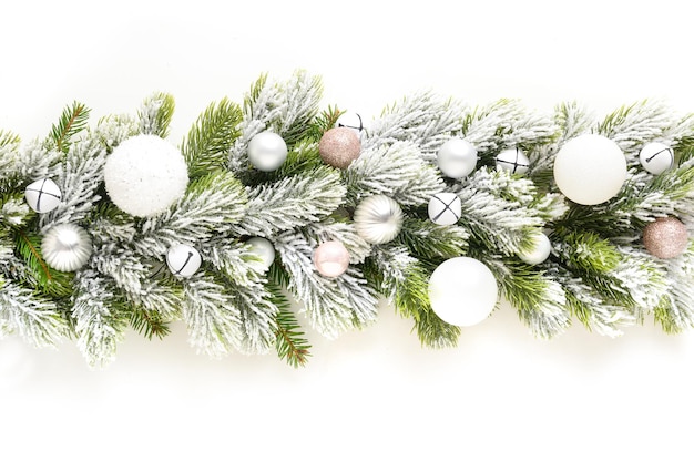 Kerstbanner met witte kerstballen in rij op besneeuwde groenblijvende takken