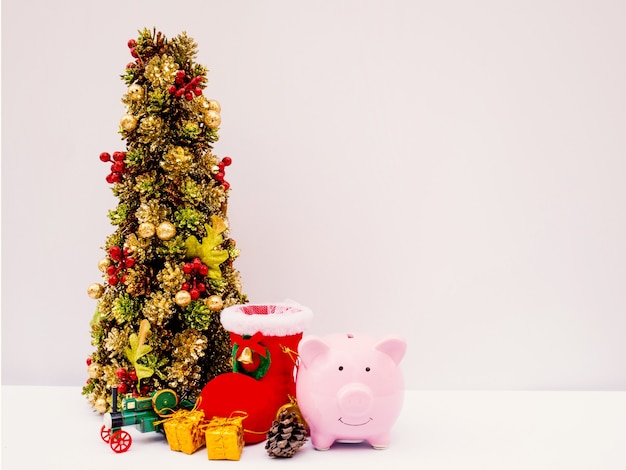 Kerstboom en roze spaarvarken met decoratieachtergrond Prettige vakantie deze kerst