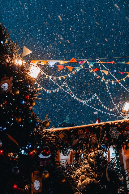 Foto kerstboom en vliegende sneeuw in het avondlicht in feestelijke magische nieuwjaarssfeer verticaal