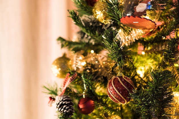 Kerstboom geassembleerd met ornamenten. Rode, zilveren en gouden ballen, geschenkdozen, lichten, de kerstman en anderen. Selectieve aandacht.