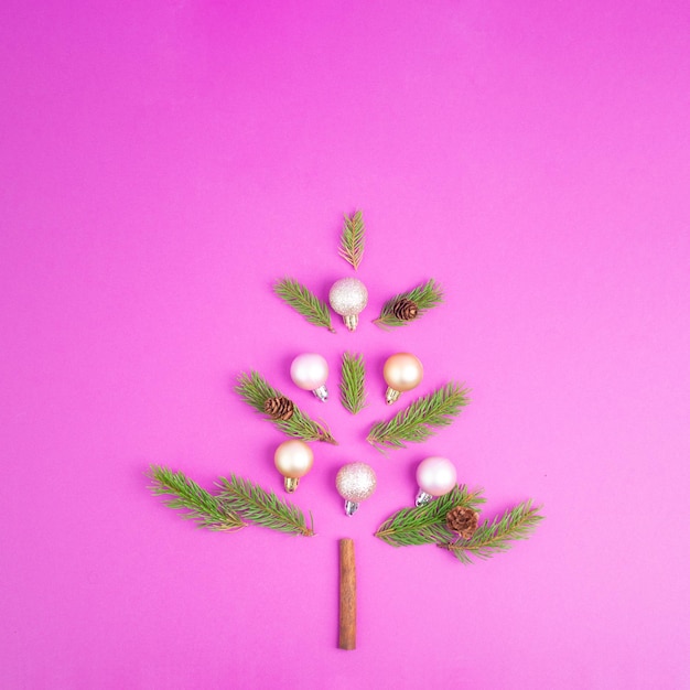 Kerstboom gemaakt van dennentakken, roze kerstballen en een kaneelstokje als stam, wenskaart