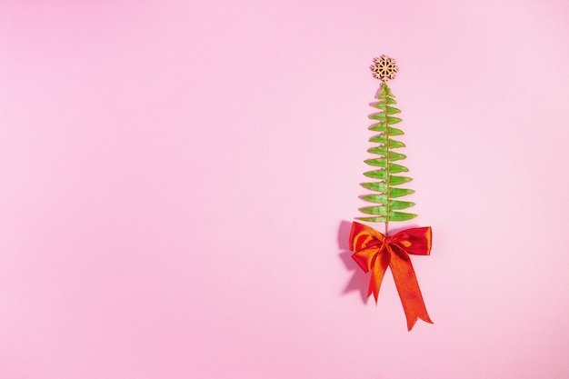 Kerstboom gemaakt van fern bladeren en takken op roze