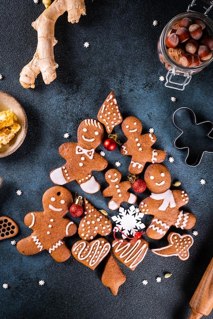 Kerstboom gemaakt van peperkoekkoekjes op donkerblauwe achtergrond met kopieerruimte voor tekst Peperkoekkoekje met keukengerei Nieuwjaar en kerstkaart Geassorteerde koekjes