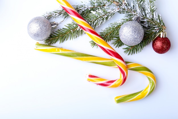 Kerstboom, geschenkdoos, lolly en gekleurde ballen op wit. copyspace.