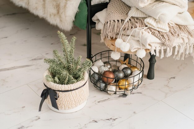 Foto kerstboom in een mand en kerstballen in een mand in het decor van een gezellig huis