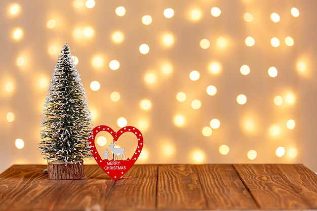 Kerstboom klok slee sneeuwman kaarsen geschenken op een houten achtergrond en lichten achtergrond