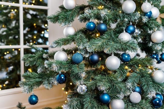 Kerstboom met blauw en zilver speelgoed Feestelijk versierde kerstboom met slingers Symbool van het nieuwe jaar