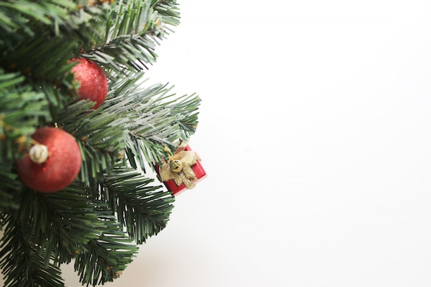 Kerstboom met decoratiesbal en doosgift op witte achtergrond.