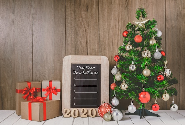 Kerstboom met kleurrijke ballenornamenten en geschenkdozen met schoolbord