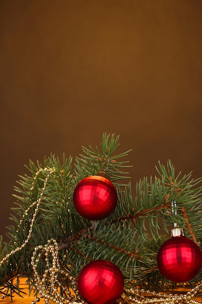 Kerstboom met mooie nieuwjaarsballen op houten tafel op bruine achtergrond