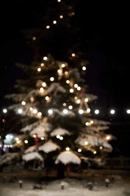 Kerstboom met slinger onscherp 's nachts. wazige lichten van slinger op kerstboom