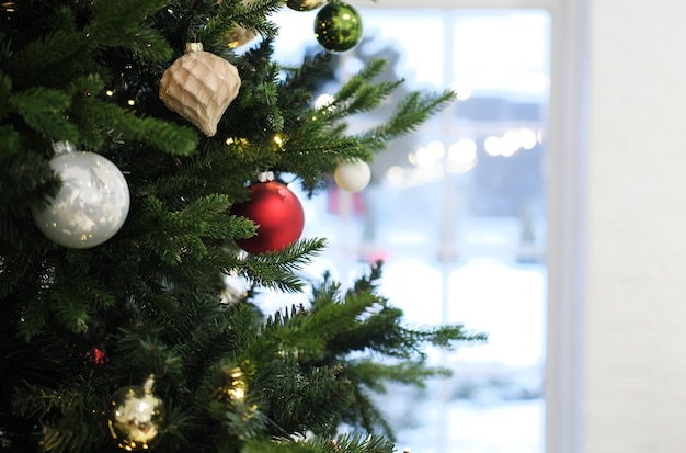 Kerstboom met speelgoed staat tegen de achtergrond van een winterraam