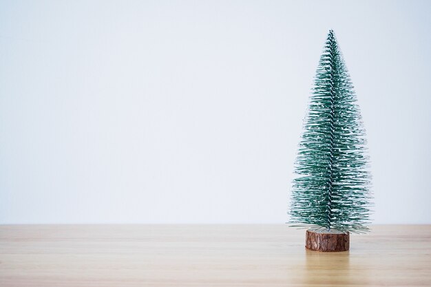 Kerstboom op houten tafel met witte muur achtergrond