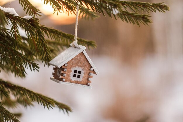 Kerstboom speelgoed houten huis op besneeuwde dennentakken Huis symbool