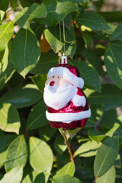 Kerstboom speelgoed in de vorm van de kerstman hangt op groene laurierbladeren