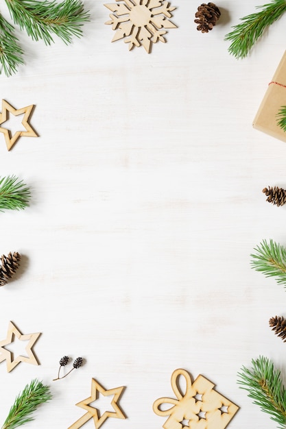 Kerstboom takken kegels en houten kerst accessoires op een witte houten achtergrond frame kopiëren ruimte samenstelling