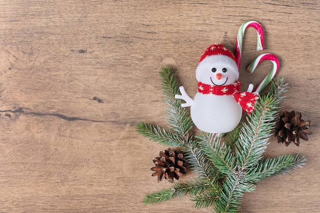 Kerstboom takken sneeuwpop speelgoed en snoep stokken op houten achtergrond met kopie ruimte bovenaanzicht.