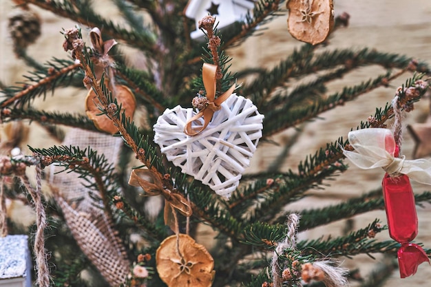 Kerstboom versierd met hartvormige rieten krans en andere handgemaakte zerowaste kerstversieringen