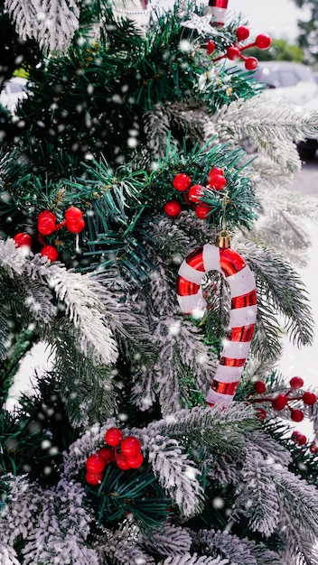 Foto kerstboomdecoratie met witte sneeuw rode en witte rietstokken vrolijk kerstfeest en gelukkige feestdagen felicitatiekaart frame banner nieuwjaar winter vakantie themaverticaal