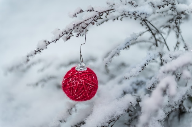 Kerstboomdecoratie van rode garenbal op natuurlijke sneeuw wordt gemaakt die