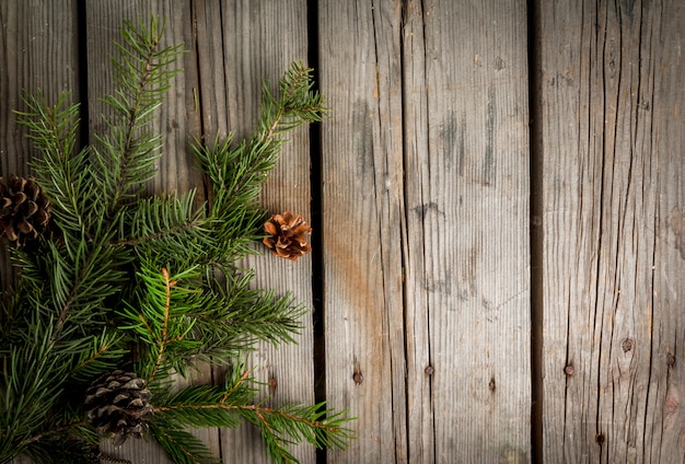 Kerstboomtak en denneappels op oude houten lijst