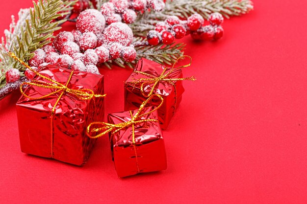 Kerstboomtak met speelgoed en een cadeau op een rode achtergrond