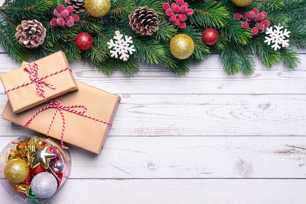 Kerstboomtak versierd met gouden ballen en geschenkdoos op witte houten achtergrond