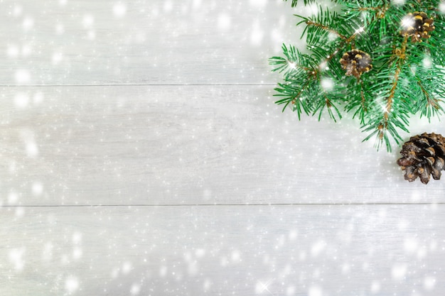 Kerstboomtakken met kegels op een lichte achtergrond, aan de rechterkant.