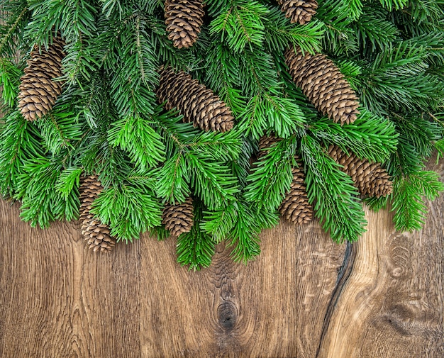 Kerstboomtakken met kegels op houten achtergrond. groene rand van onversierde groenblijvende twijgen