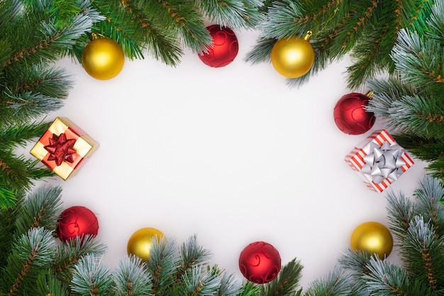 Foto kerstboomtakken op witte achtergrond met kerstmis rode en gouden ballen