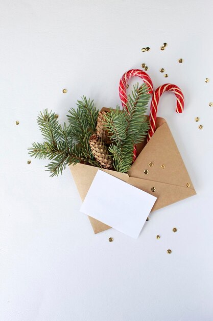 Kerstbriefenvelop met blanco papieren kaart, witte geschenkdoos met gouden strik, dennentakken versierde ballen op donkerblauwe achtergrond. Plat lag, bovenaanzicht. Brief aan het concept van de Kerstman.