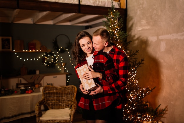 Kerstcadeau. Gelukkige paar met Kerstmis en Nieuwjaarsgift thuis. Glimlachende familie samen. kerstboom