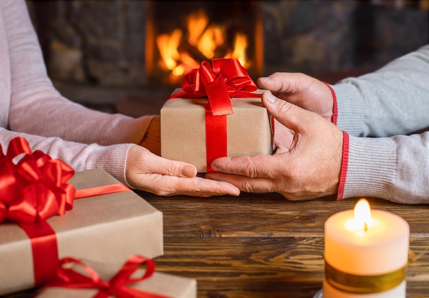 Kerstcadeau in handen Gelukkige man geeft Kerstmis en Nieuwjaar Geschenkdoos aan vrouw thuis Familie Kerstviering Persoon die een geschenkdoos ontvangt Kerstversiering Relatie